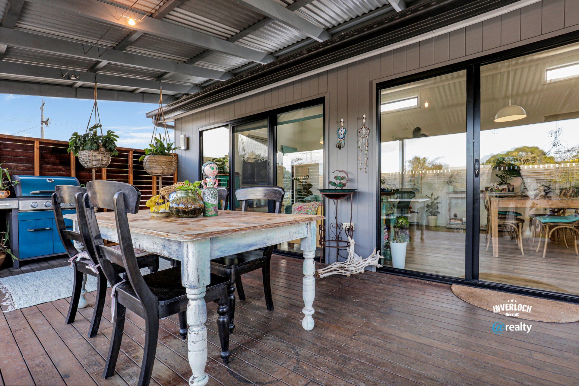 There is a table and chairs on the deck of a house.