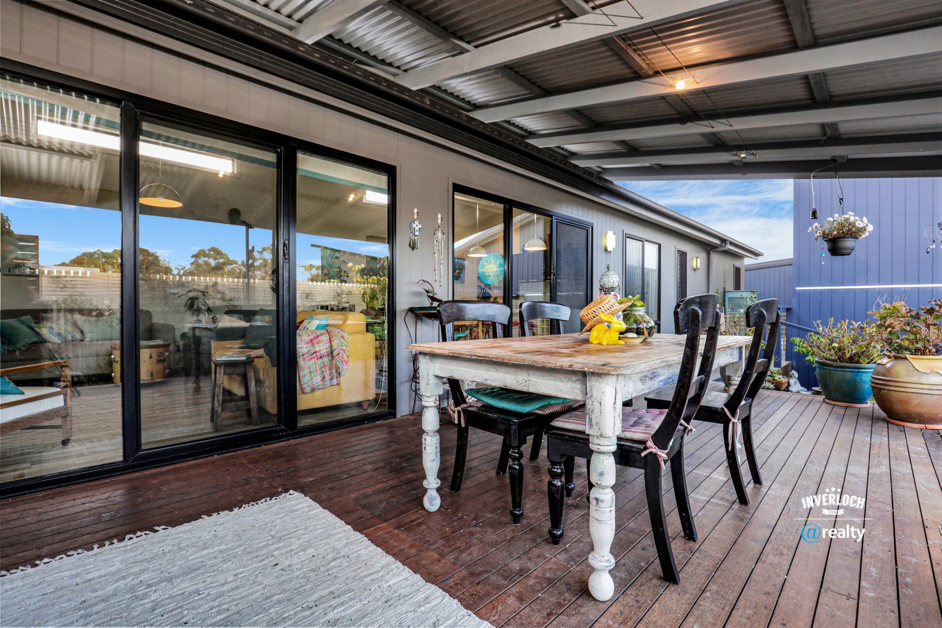 There is a table and chairs on the deck of a house.