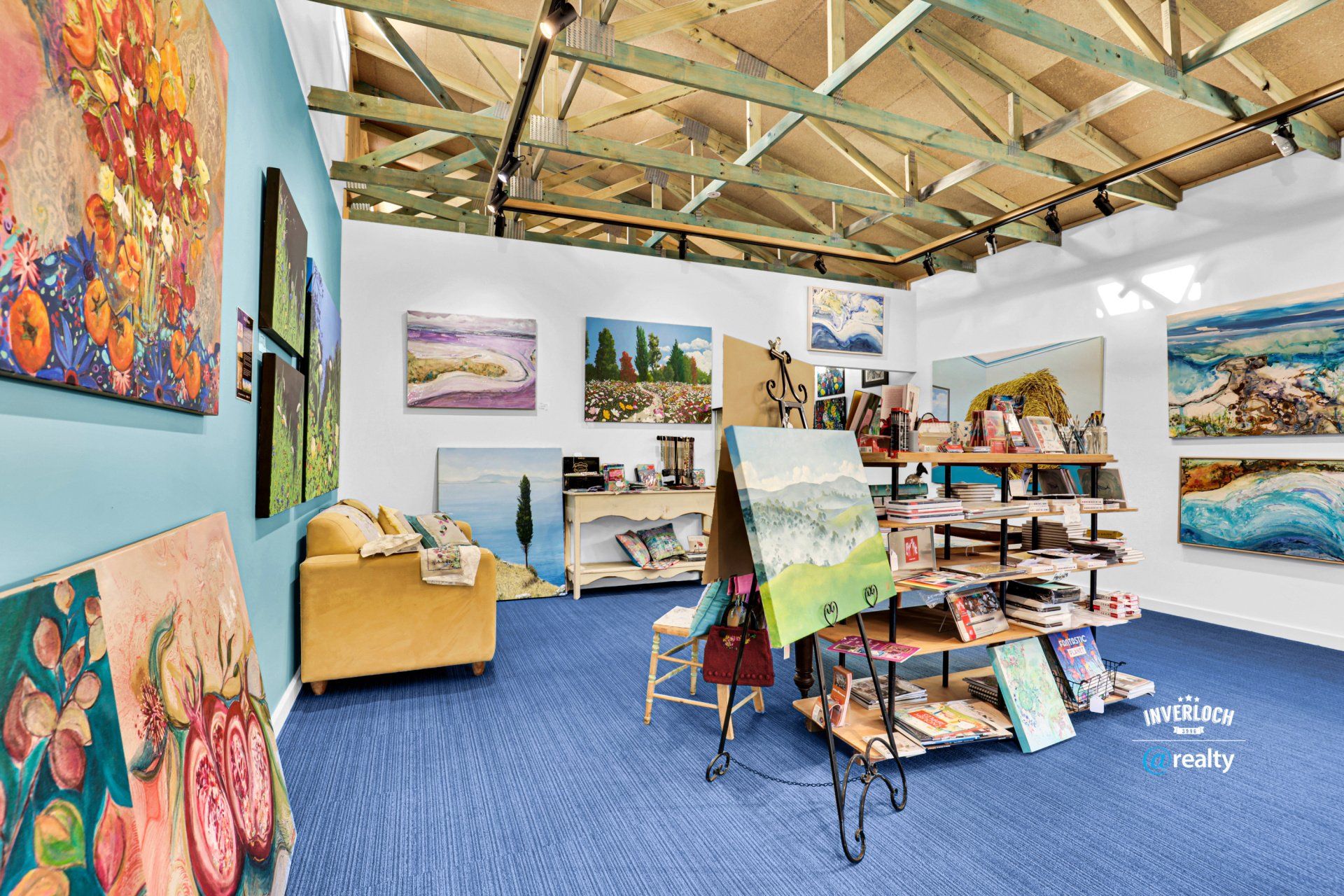 A room with a lot of paintings on the walls and a blue carpet.