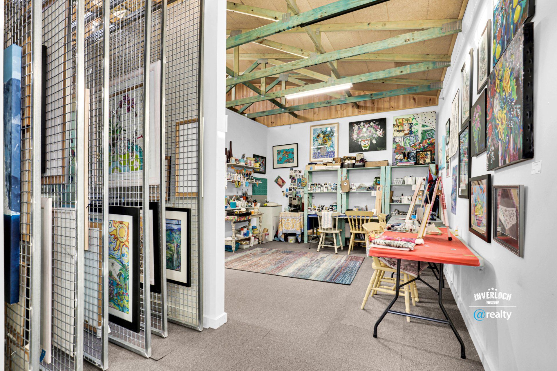 A woman is standing in a room filled with paintings and a table.