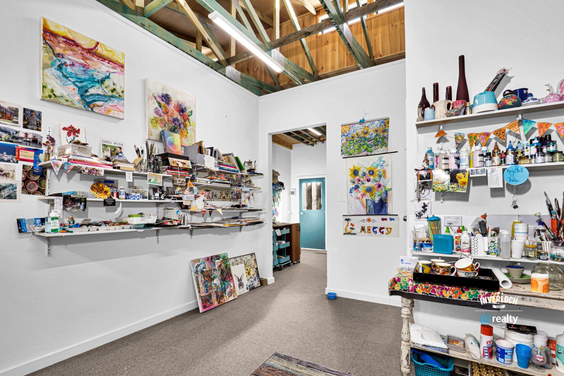 A room with a lot of shelves and paintings on the wall.