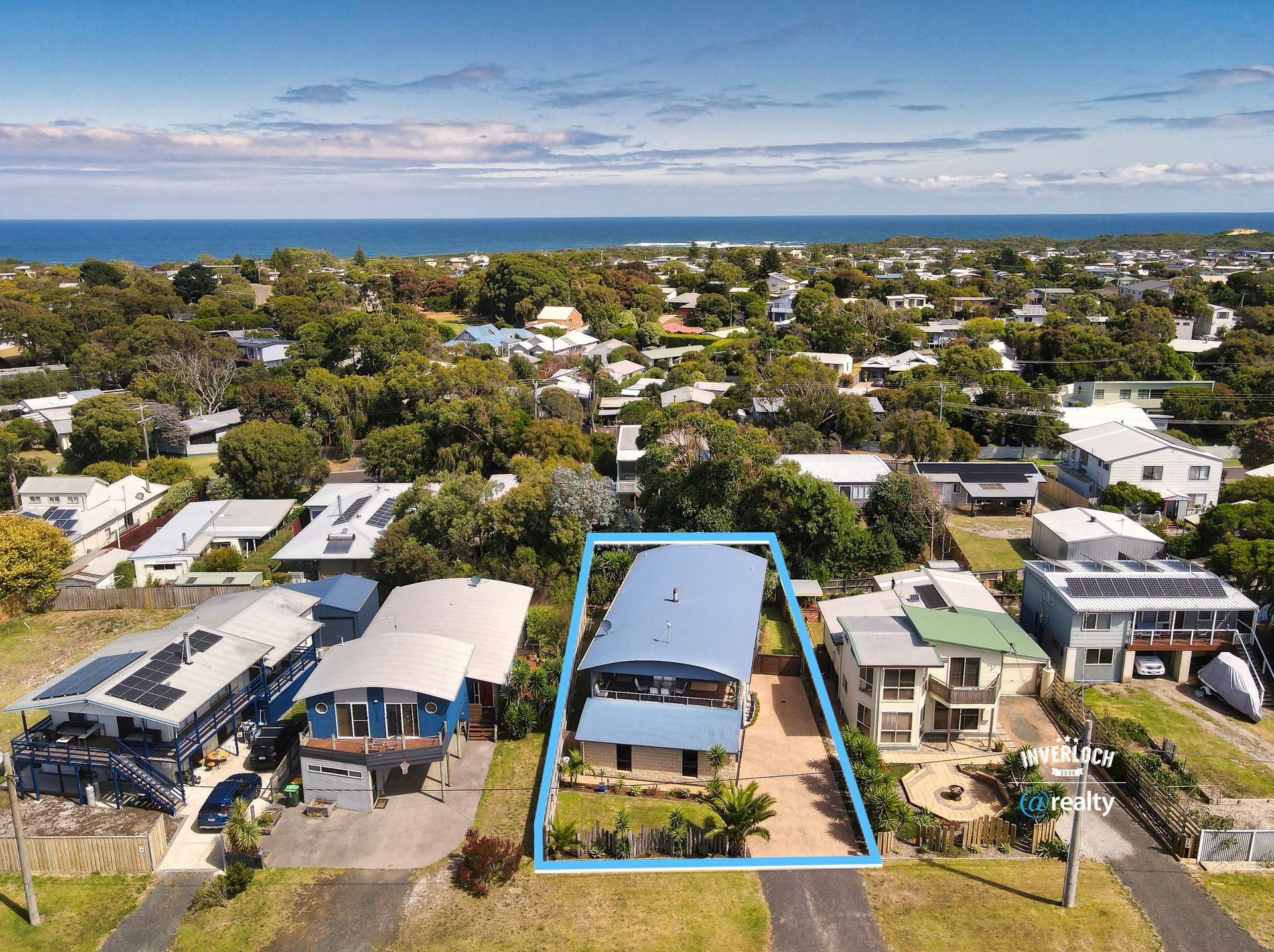 Aerial view of houses in a coastal town, with a blue outline around a two-story home with a blue roof.