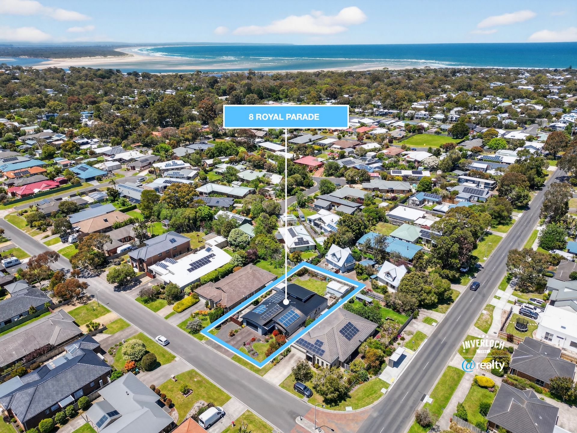 Aerial view of houses in a coastal town with the marked property: 8 Royal Place. Ocean and trees in the background.