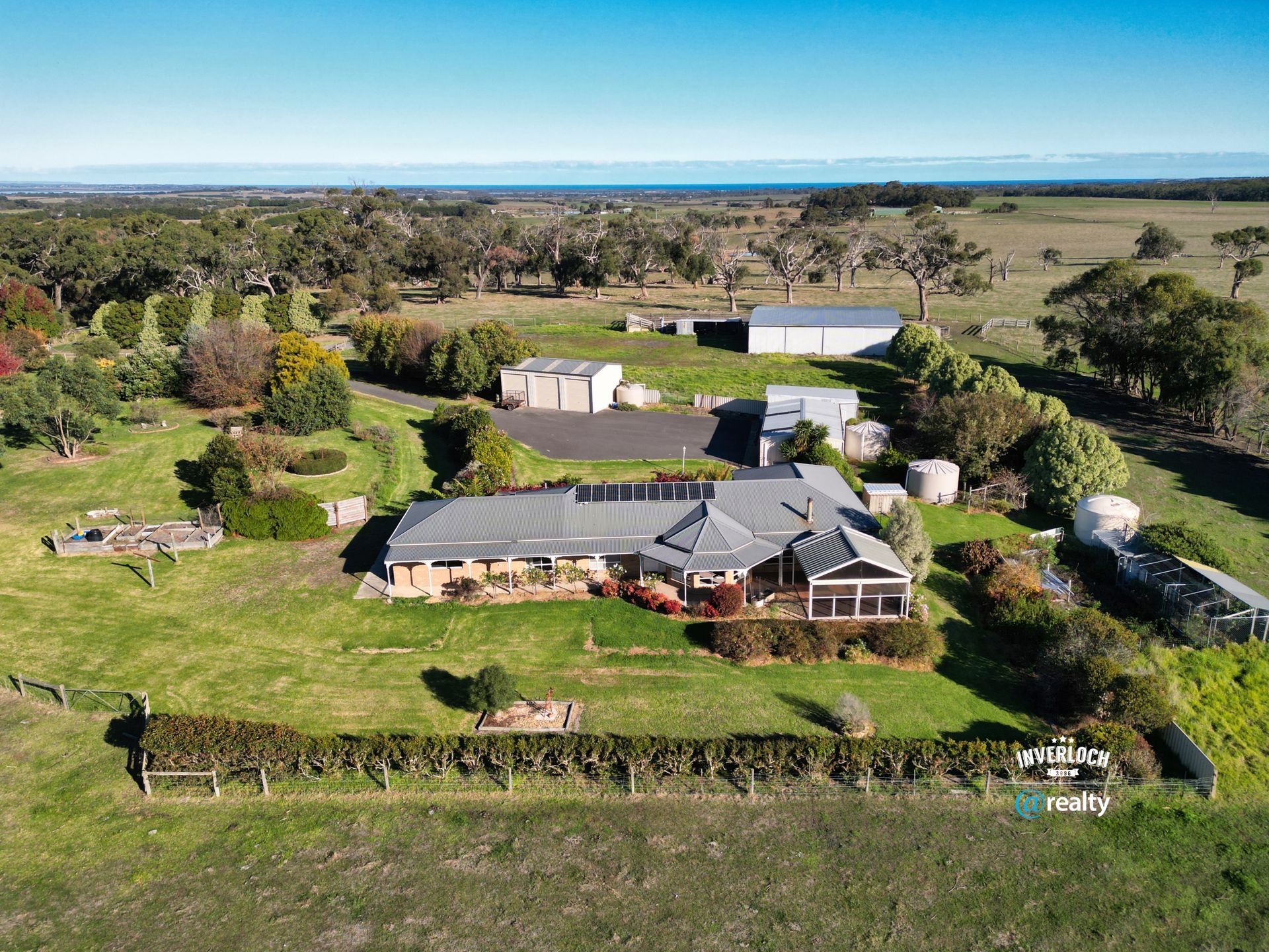 An aerial view of a large lush green field with a house in the middle.
