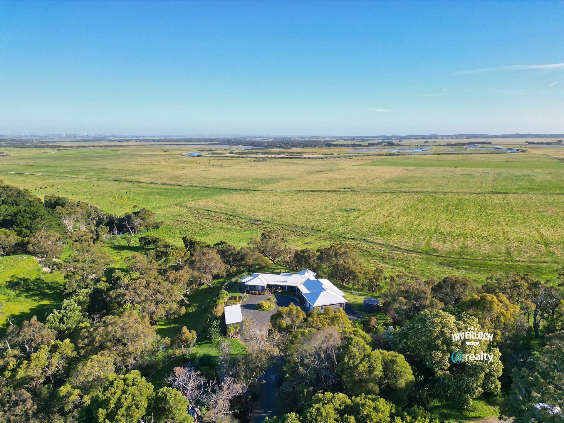 House in a field at sunset, surrounded by trees.