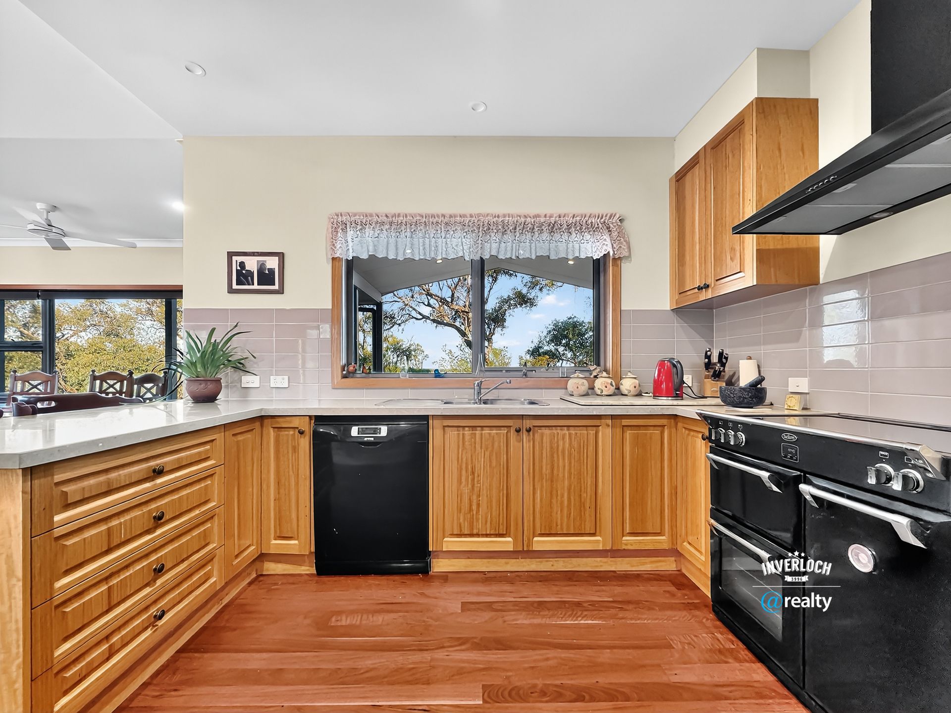 Kitchen with wood cabinets, black appliances, and a window overlooking trees.