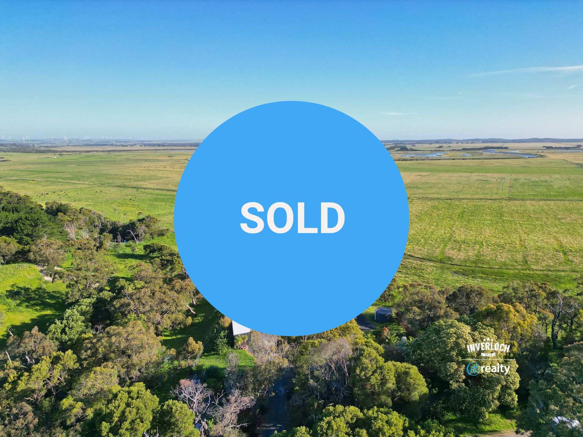 House in a field at sunset, surrounded by trees.