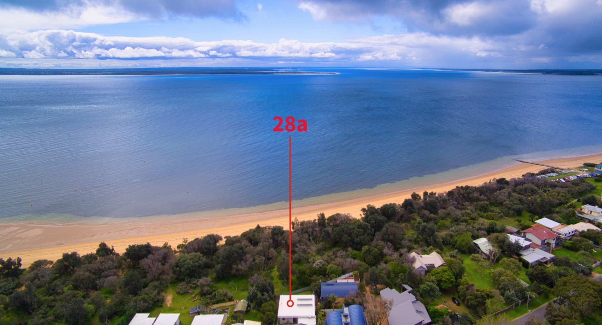 An aerial view of a beach with a house in the distance.