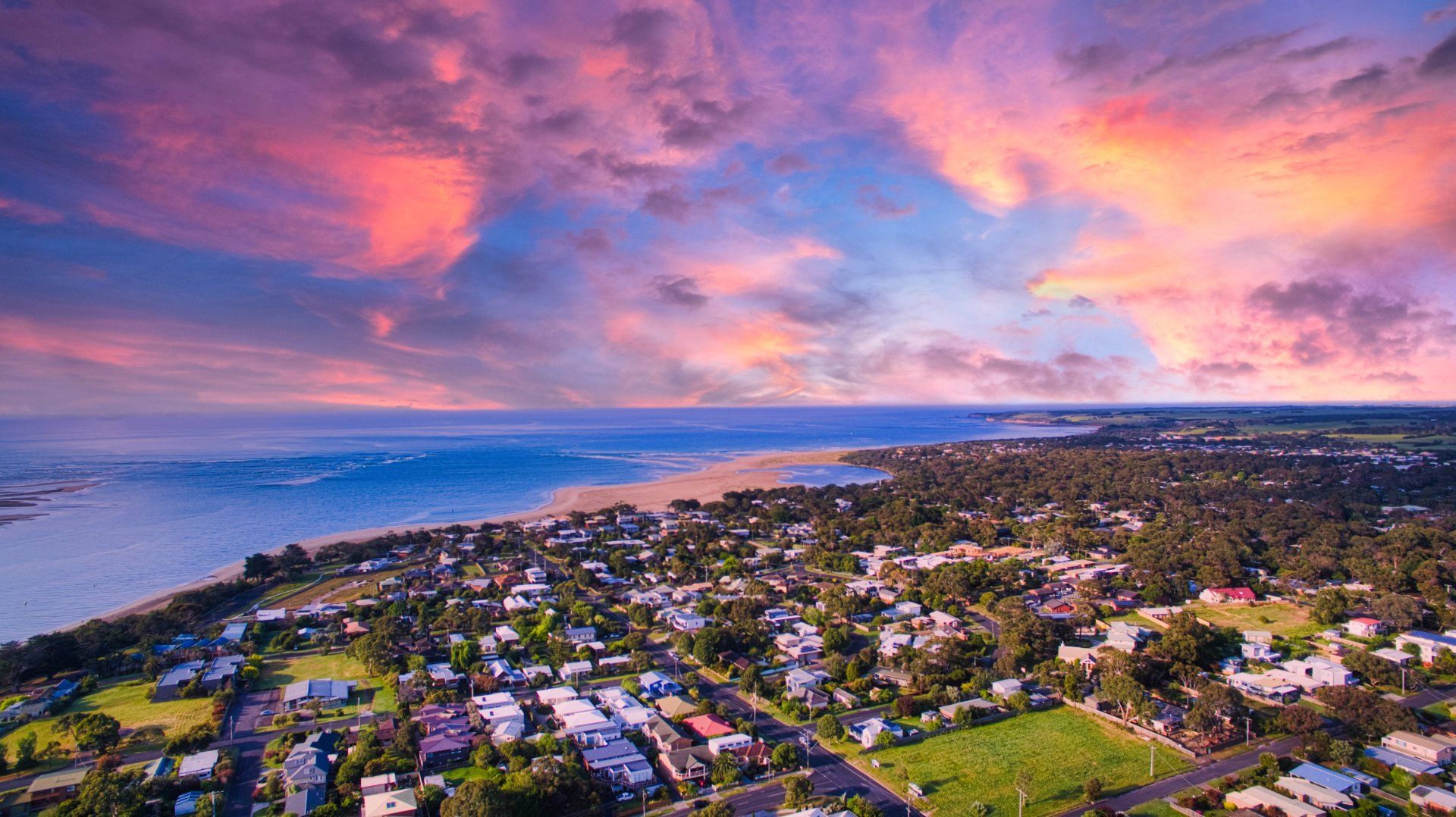 An aerial view of a small town next to the ocean at sunset.