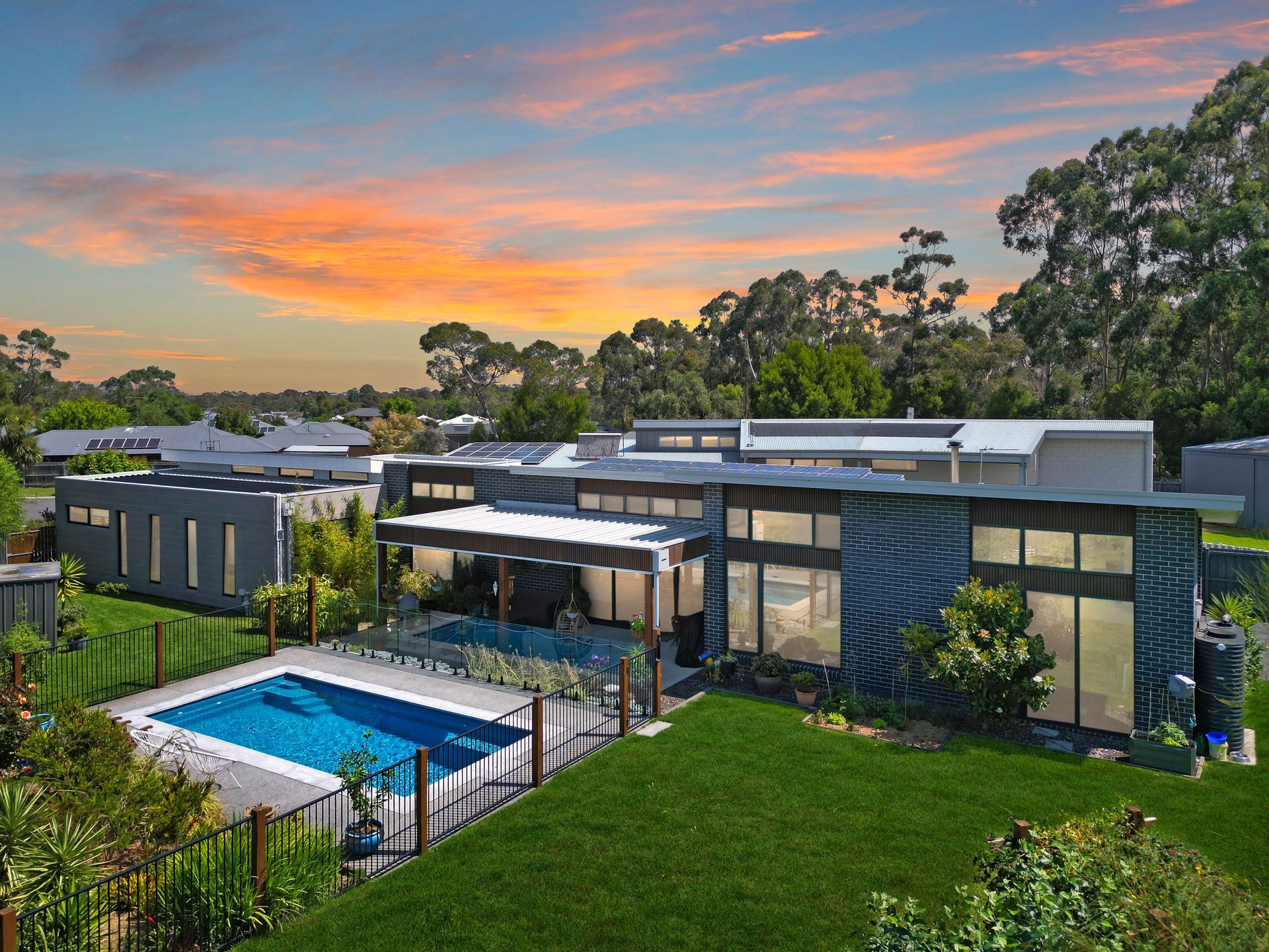 A large house with a swimming pool in the backyard at sunset.