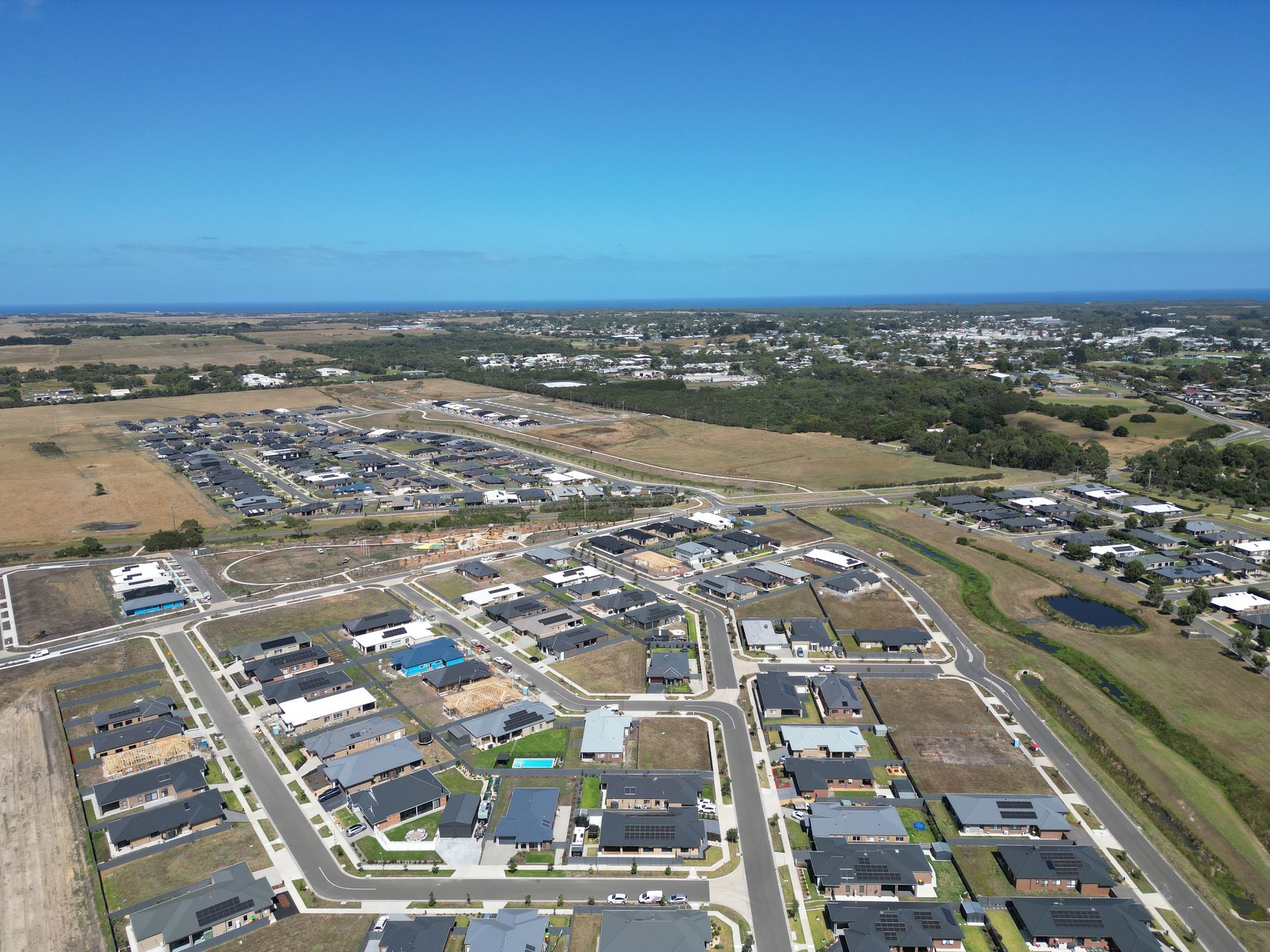 An aerial view of a sprawling residential suburban development featuring rows of houses near an open grassy field.