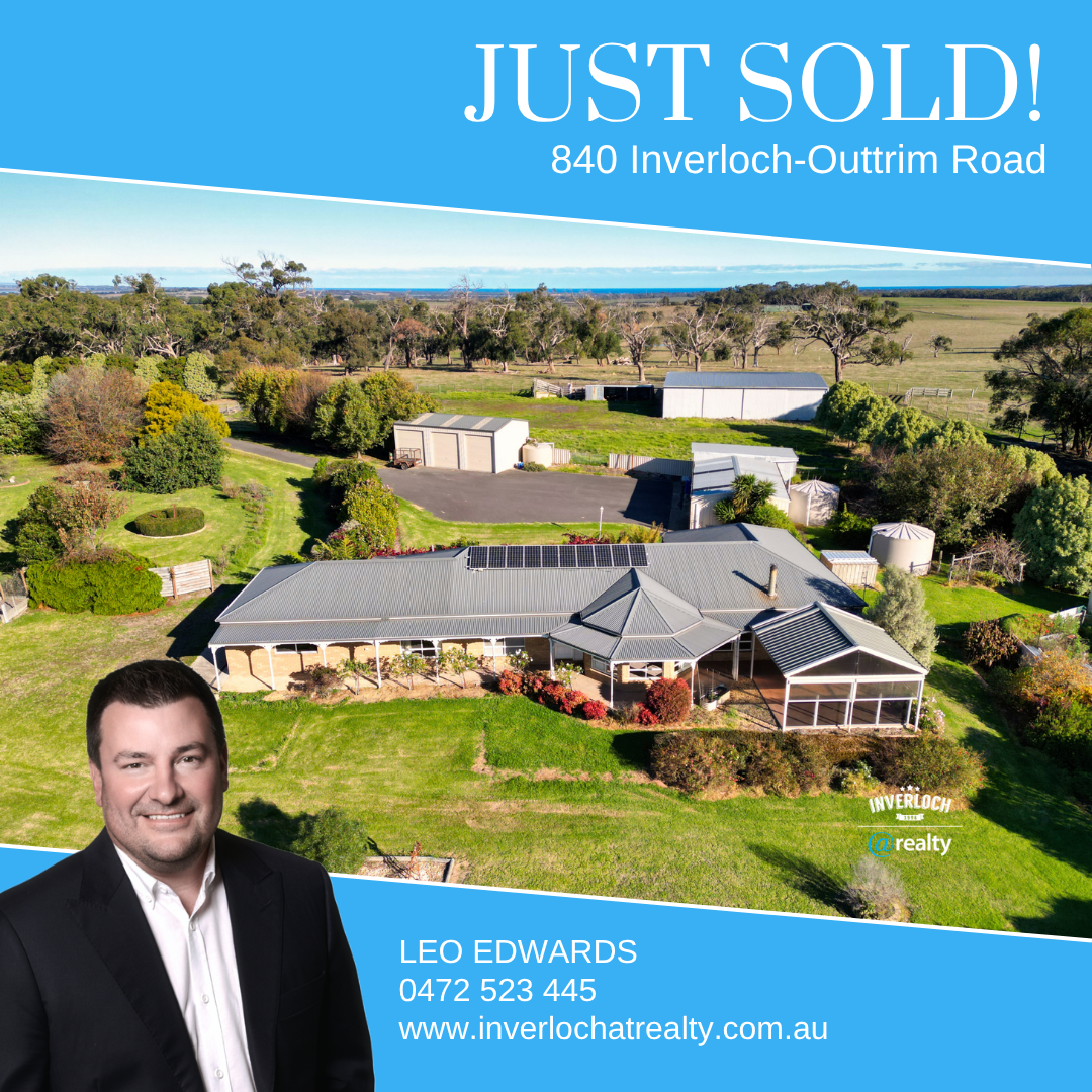A man in a suit is standing in front of a house that has just been sold