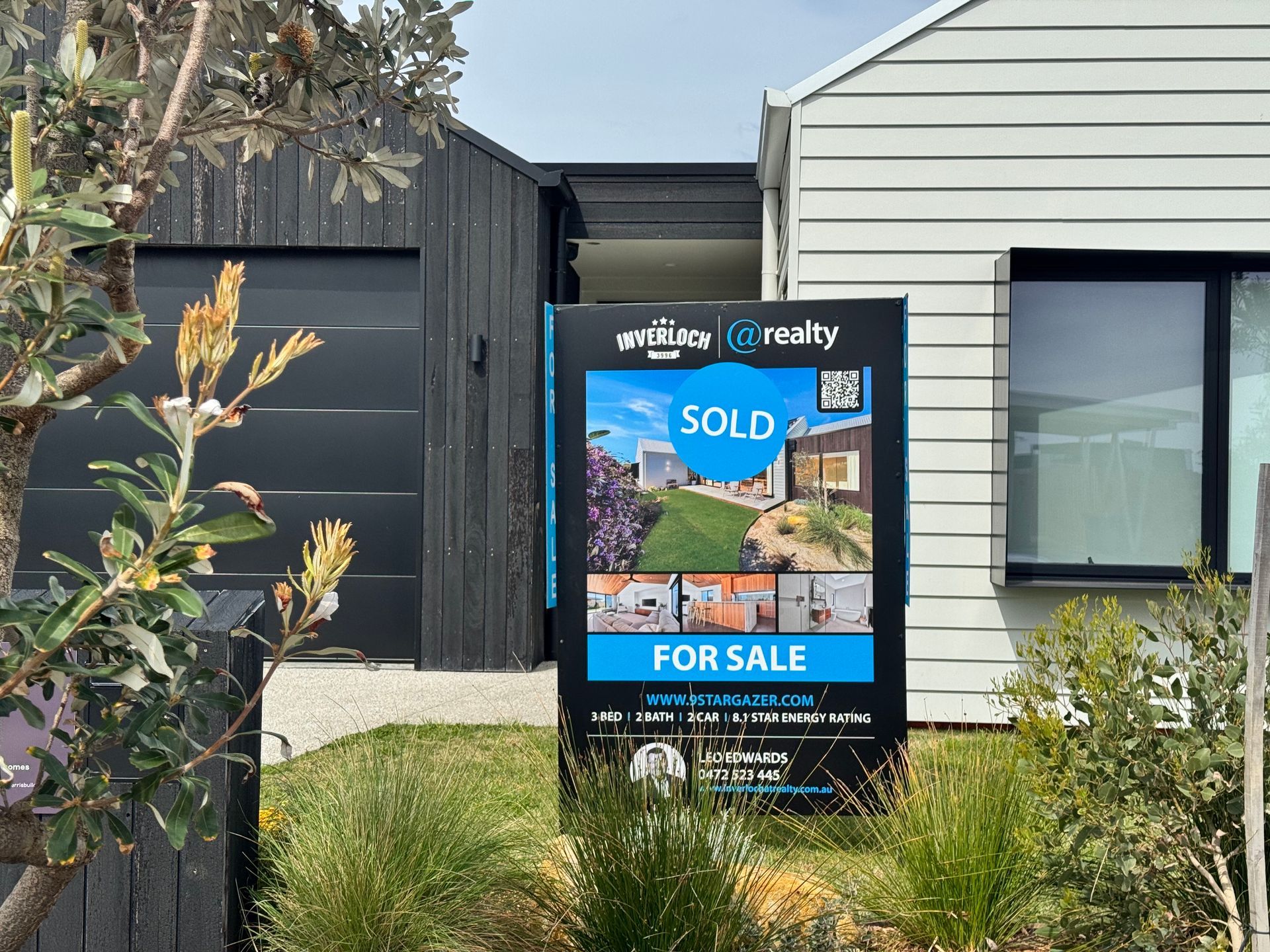 Real estate sign in front of a modern house, 