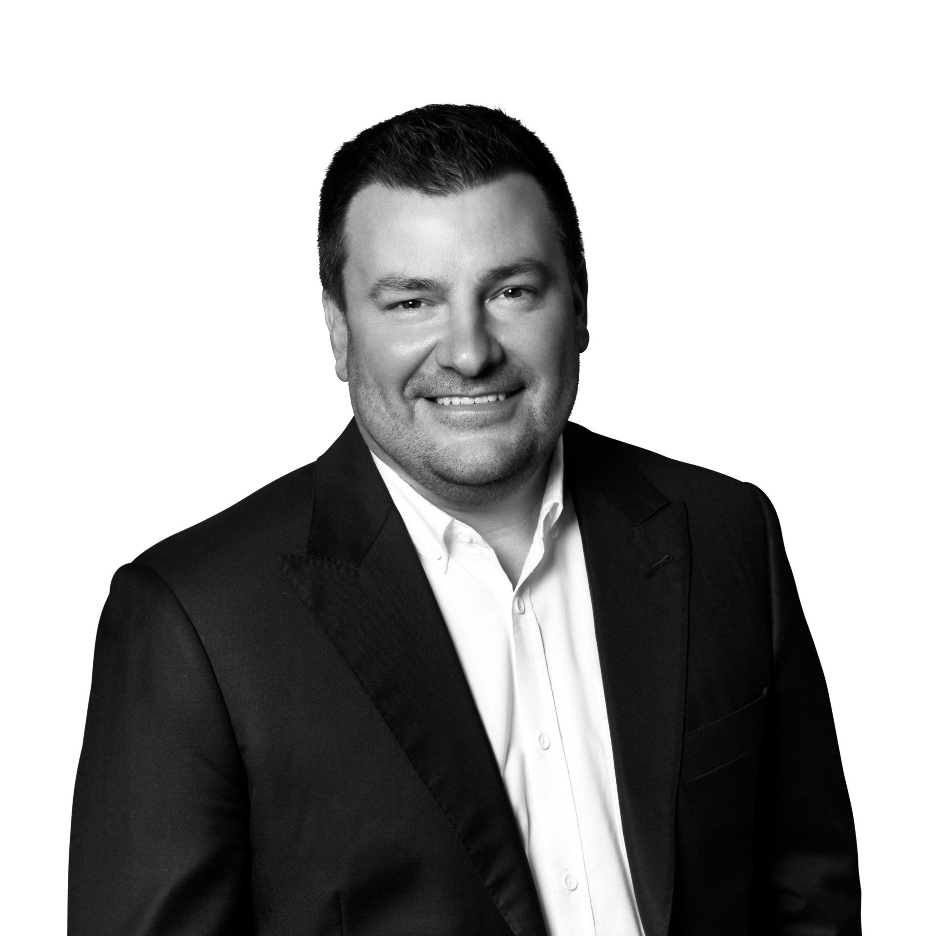 A man in a suit and white shirt is smiling in a black and white photo.