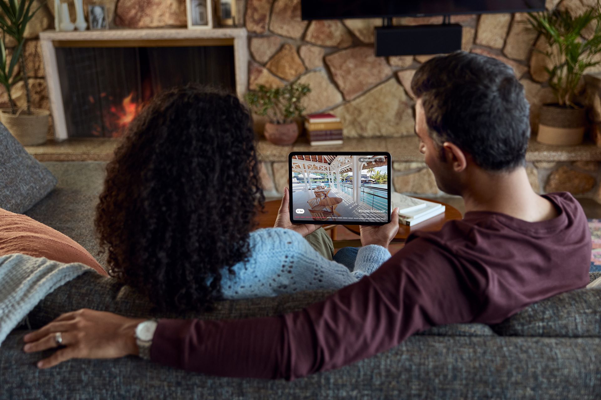 A man and a woman are sitting on a couch looking at a tablet.