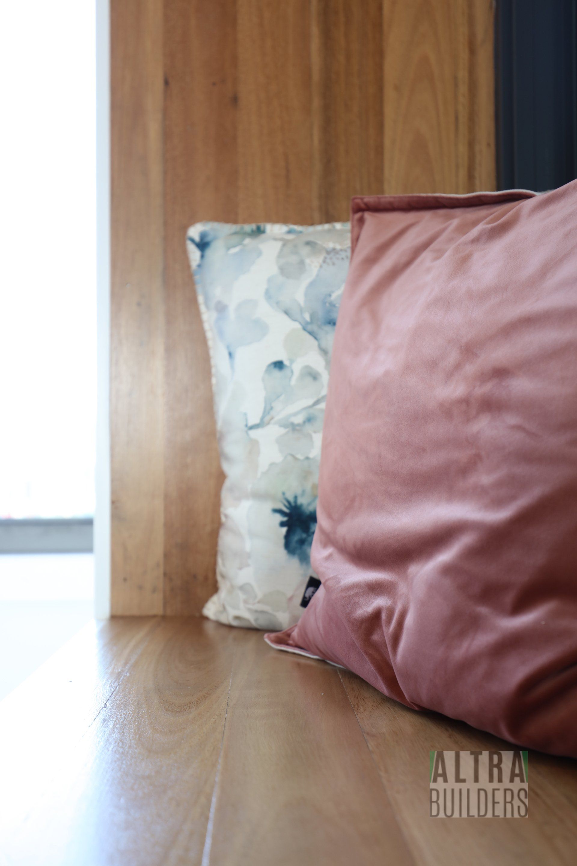 Two pillows are sitting on a wooden bench next to a window.