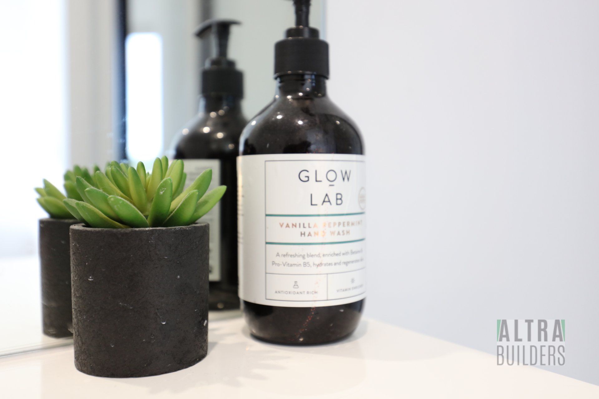 A bottle of glow lab soap is sitting on a counter next to a potted plant.