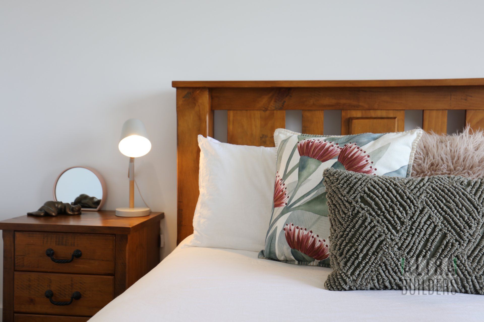 A bedroom with a bed , nightstand , lamp and pillows