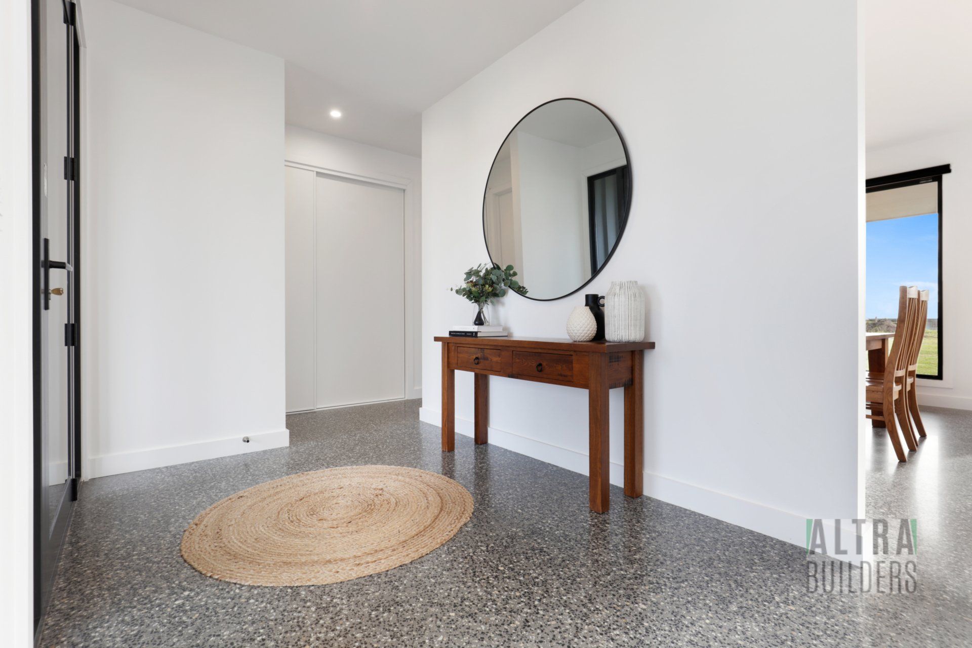 A hallway with a round mirror and a wooden table