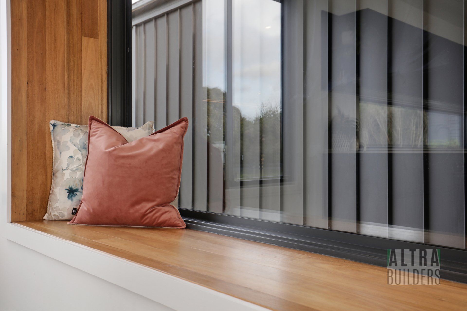 A pillow is sitting on a window sill next to a window.