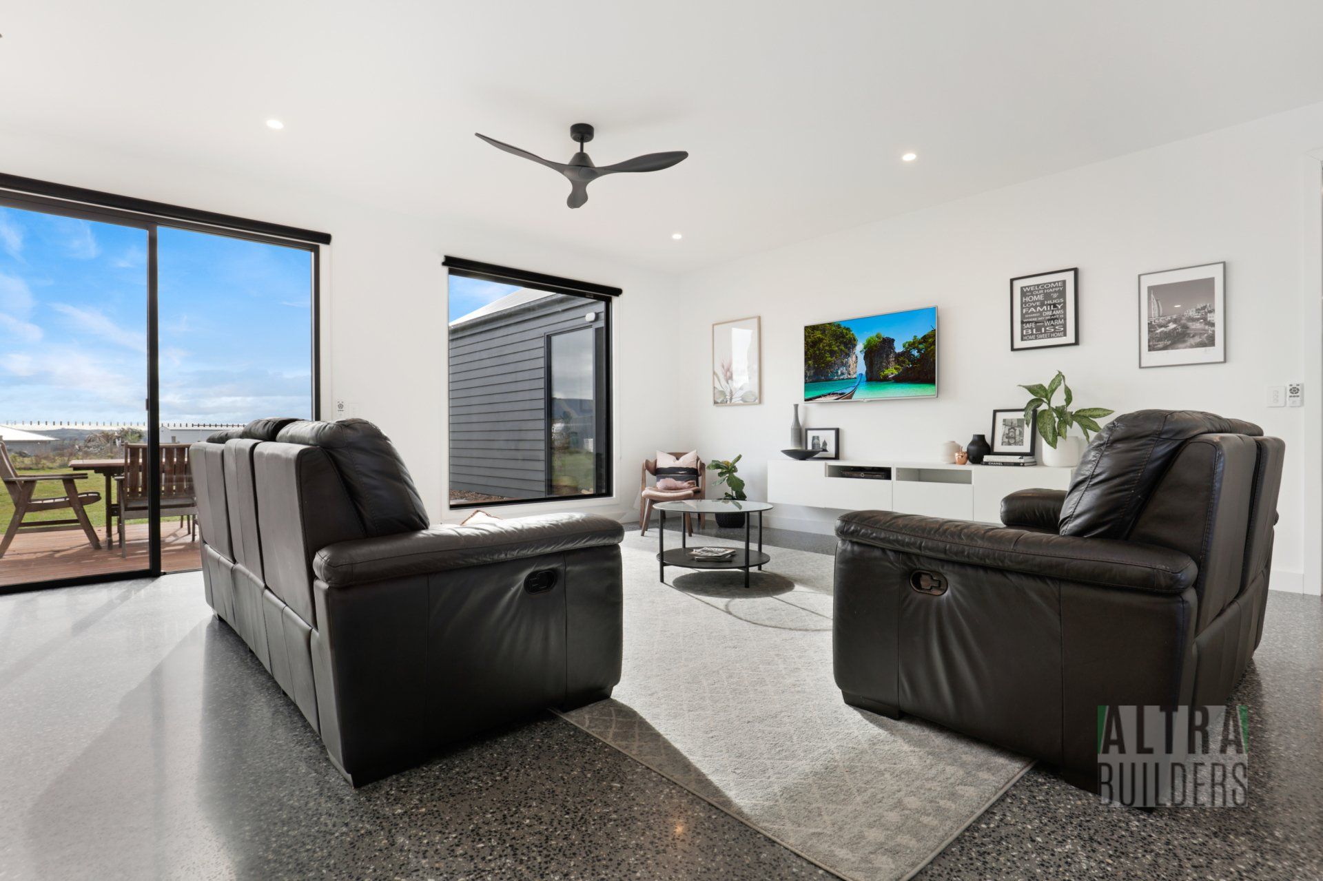 A living room with a couch and two chairs and a ceiling fan.