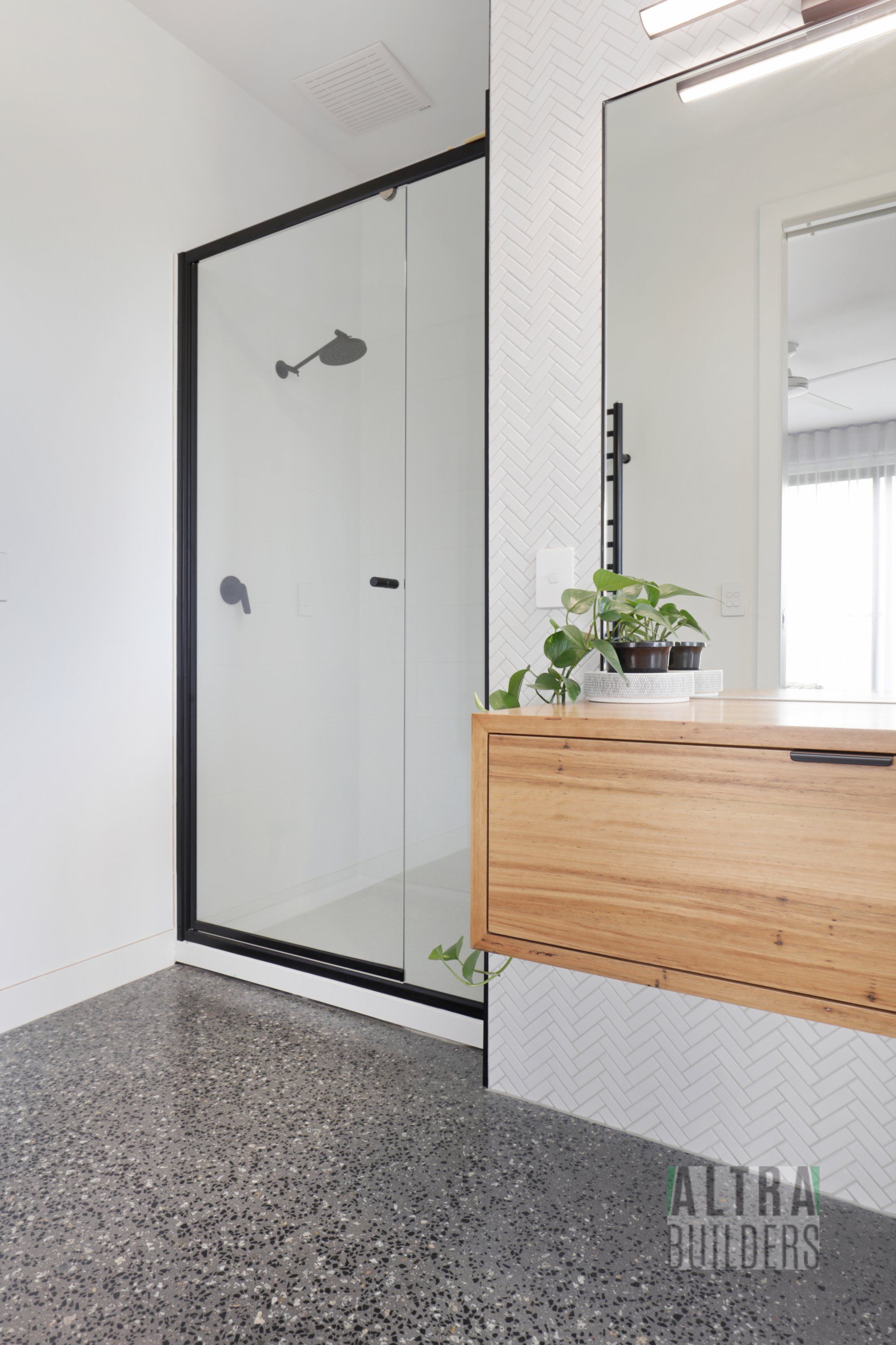 A bathroom with a walk in shower and a wooden vanity.
