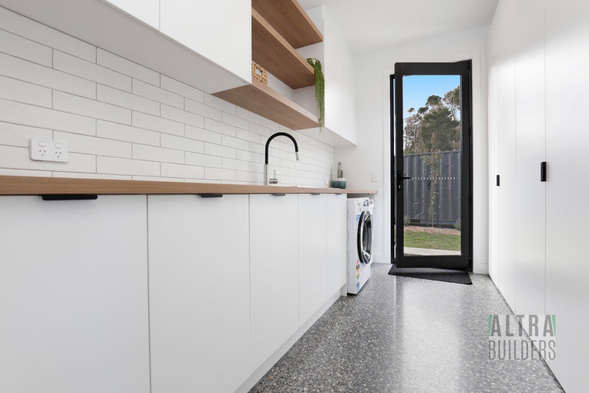 A laundry room with white cabinets and a washing machine