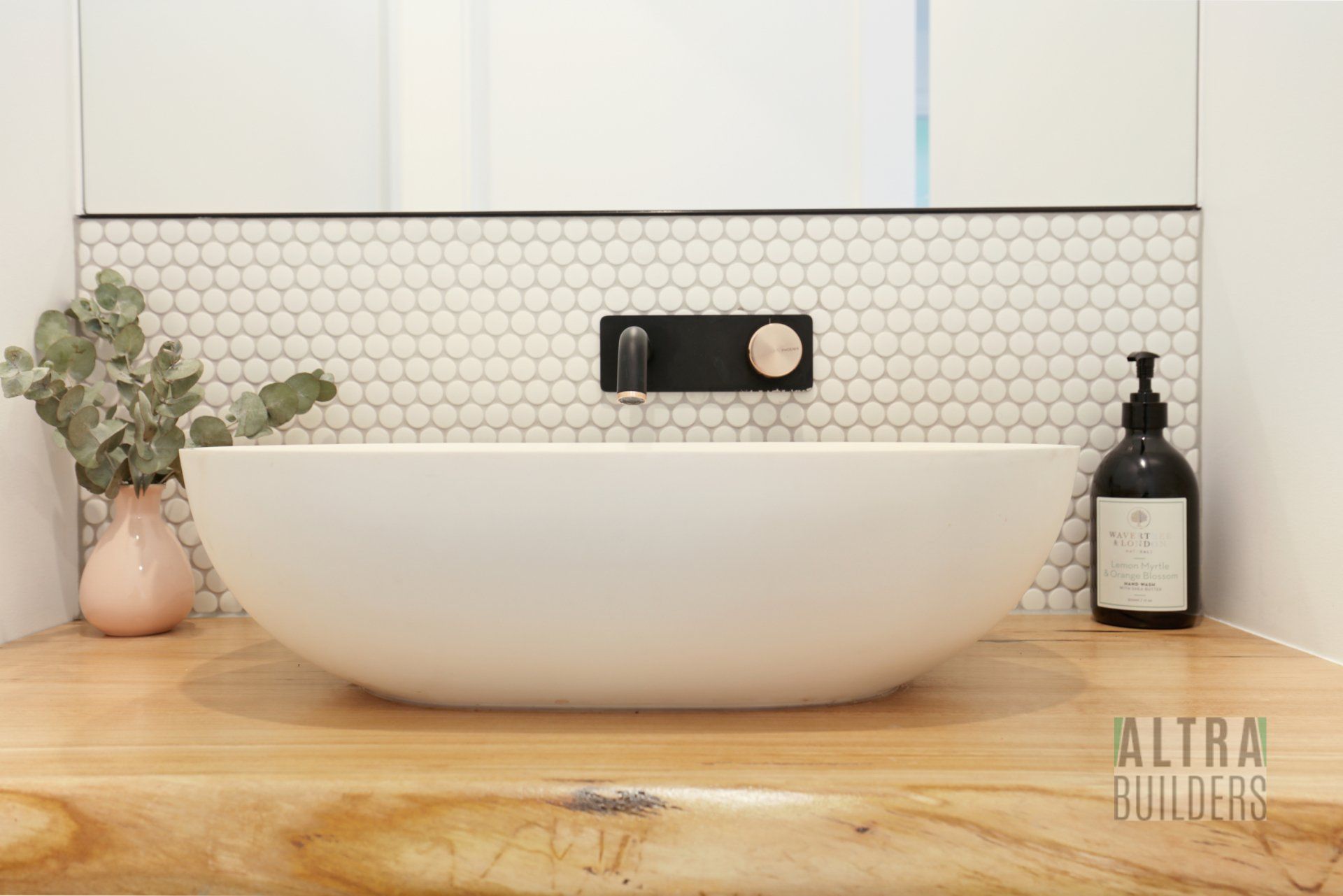 A bathroom sink is sitting on top of a wooden counter.