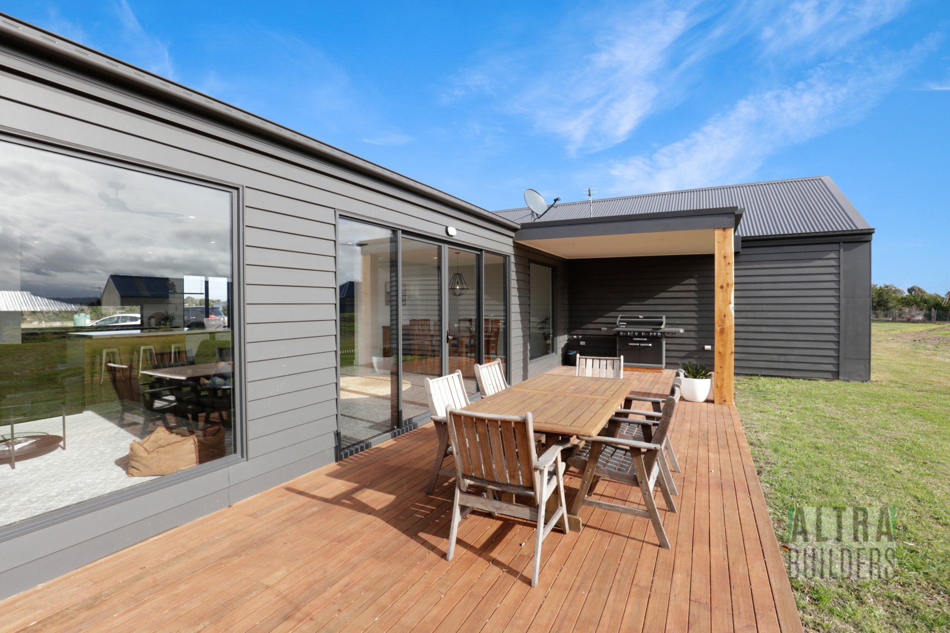 A wooden deck with a table and chairs in front of a house