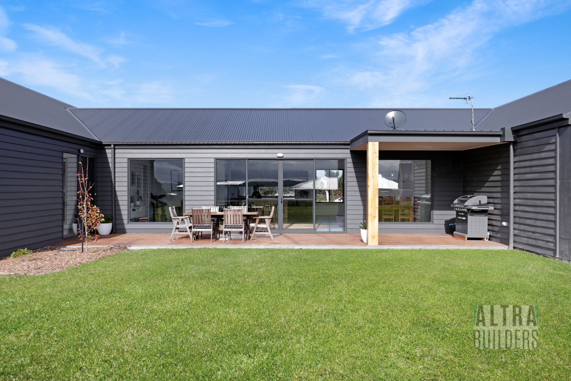 The backyard of a house with a large lawn and a table and chairs.