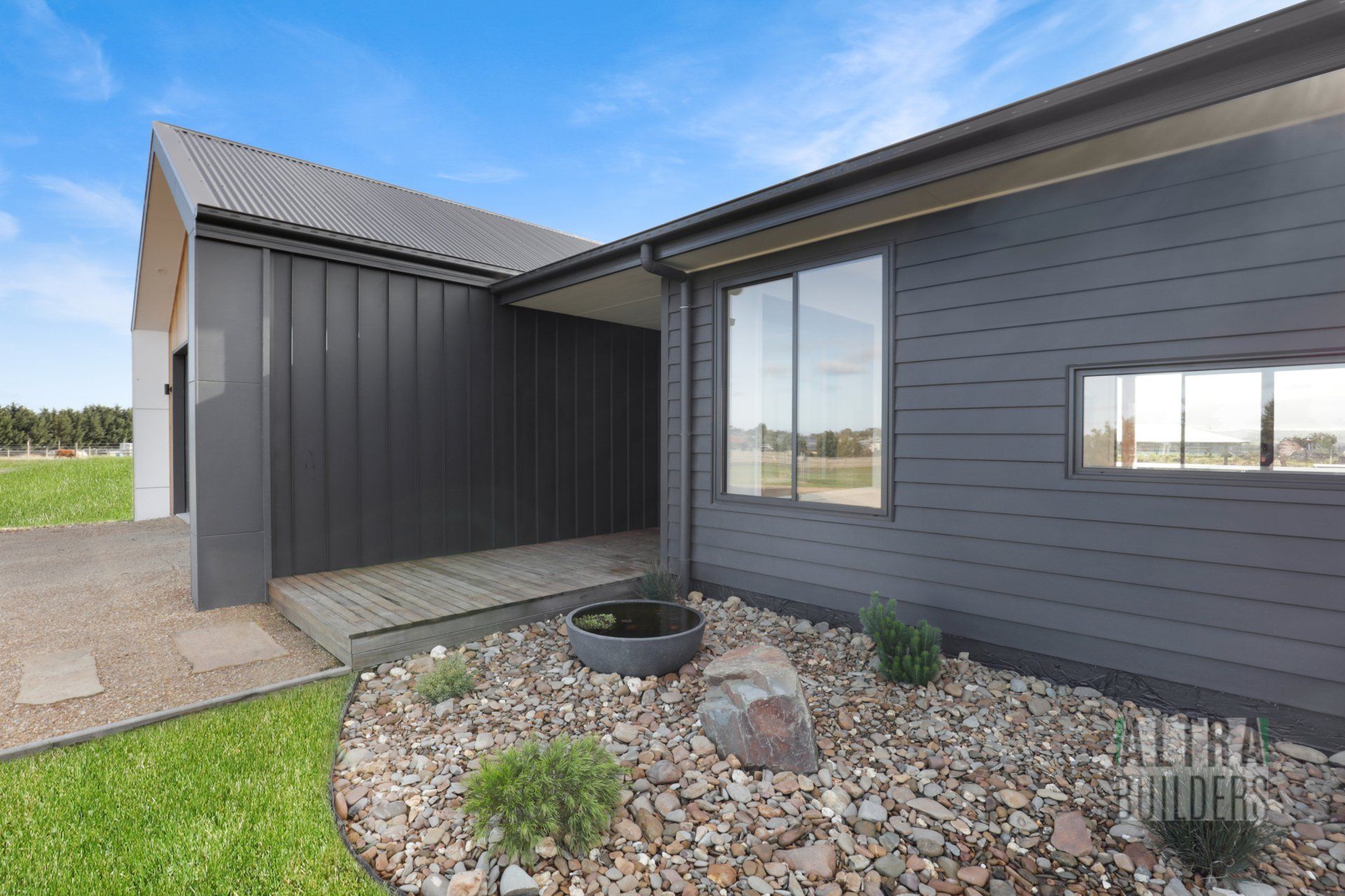 A house with a lot of windows and a lot of rocks in front of it.