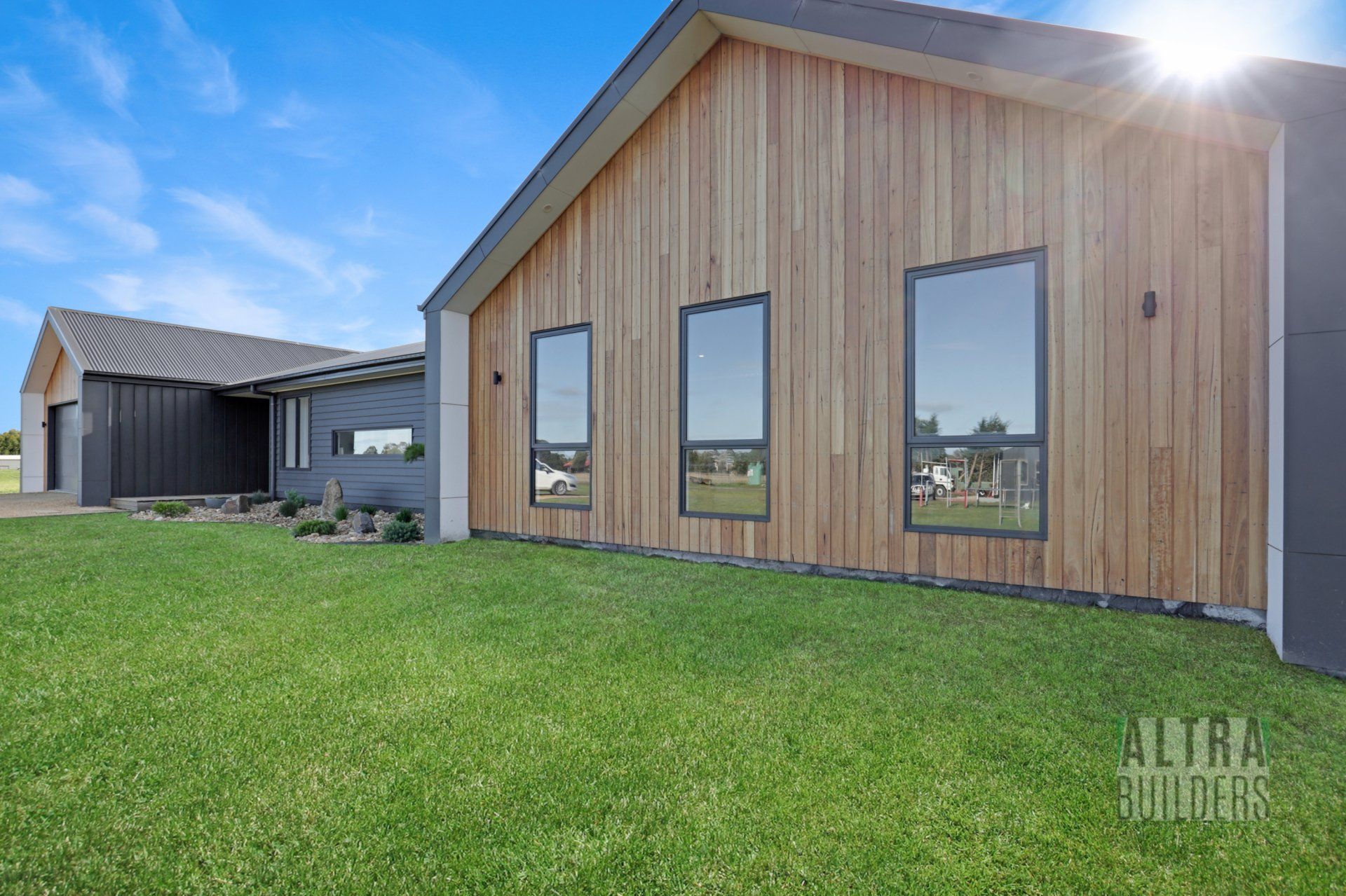 A large house with a lot of windows is sitting on top of a lush green field.