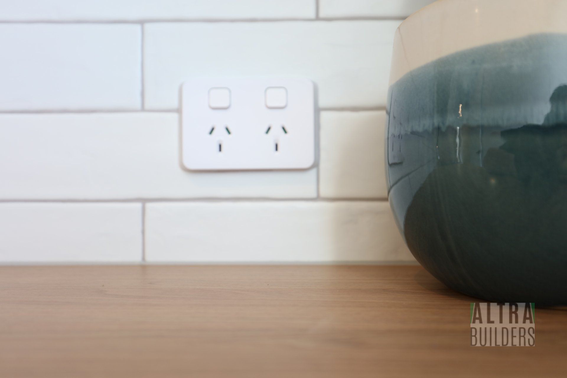 A bowl is sitting on a wooden counter next to an electrical outlet.