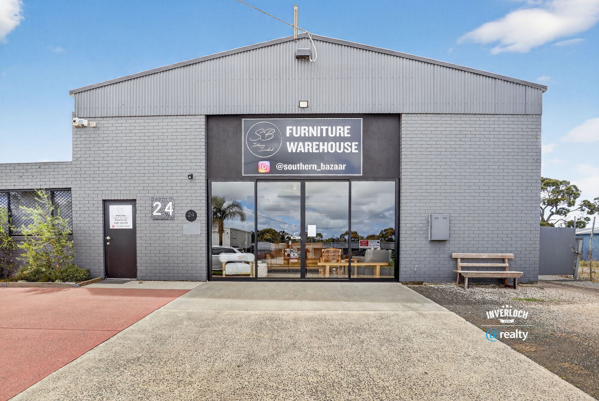 Furniture Warehouse exterior with glass front, gray building, sign, and entryway.