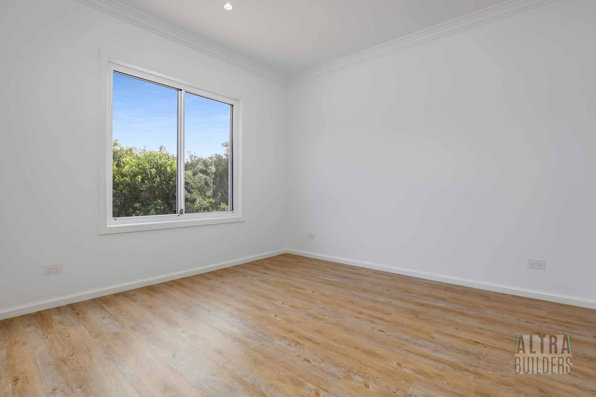 An empty room with hardwood floors and a window.