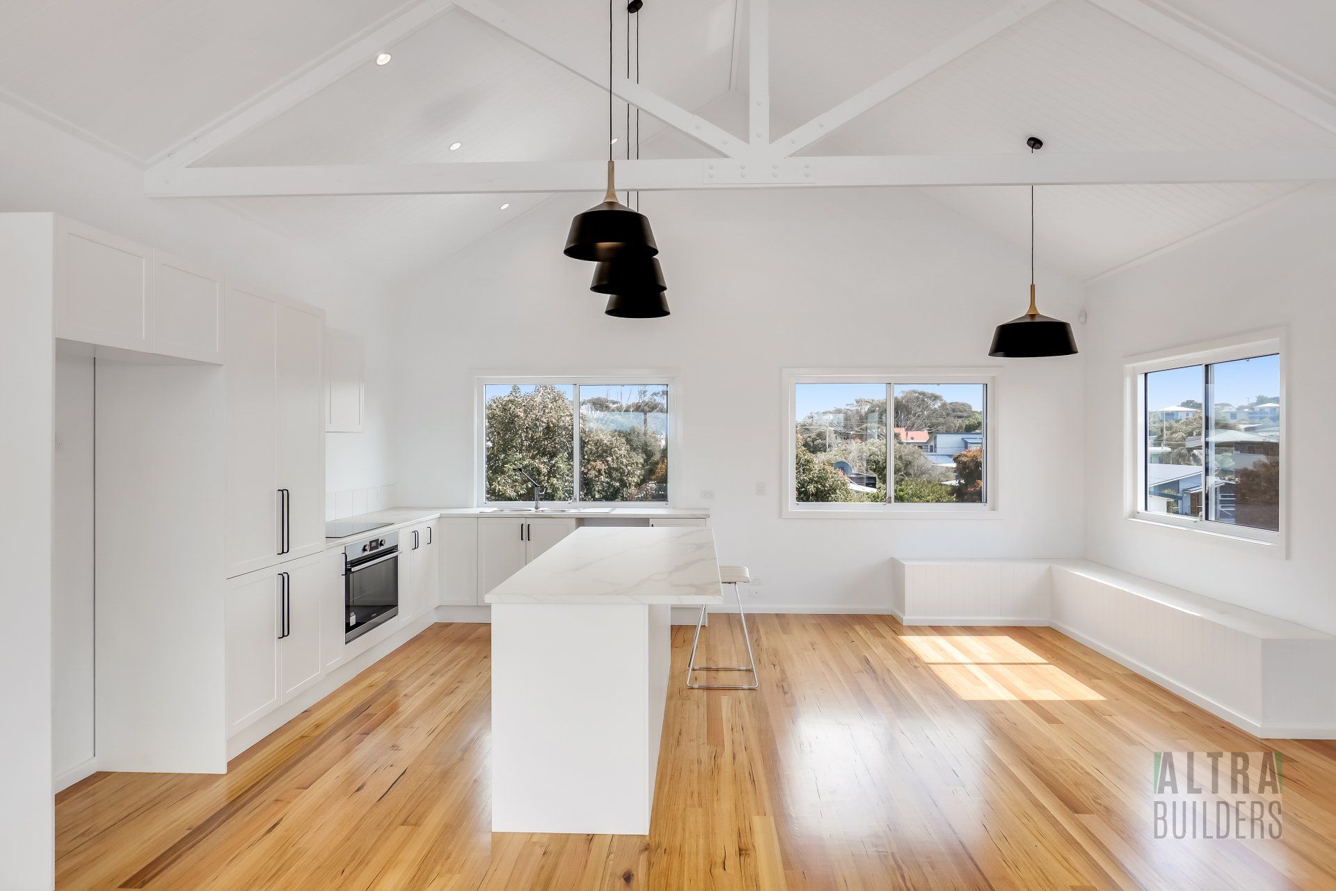 An empty kitchen with white cabinets and wooden floors