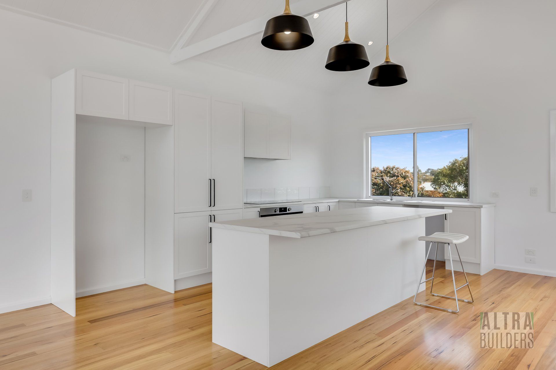 An empty kitchen with white cabinets and wooden floors