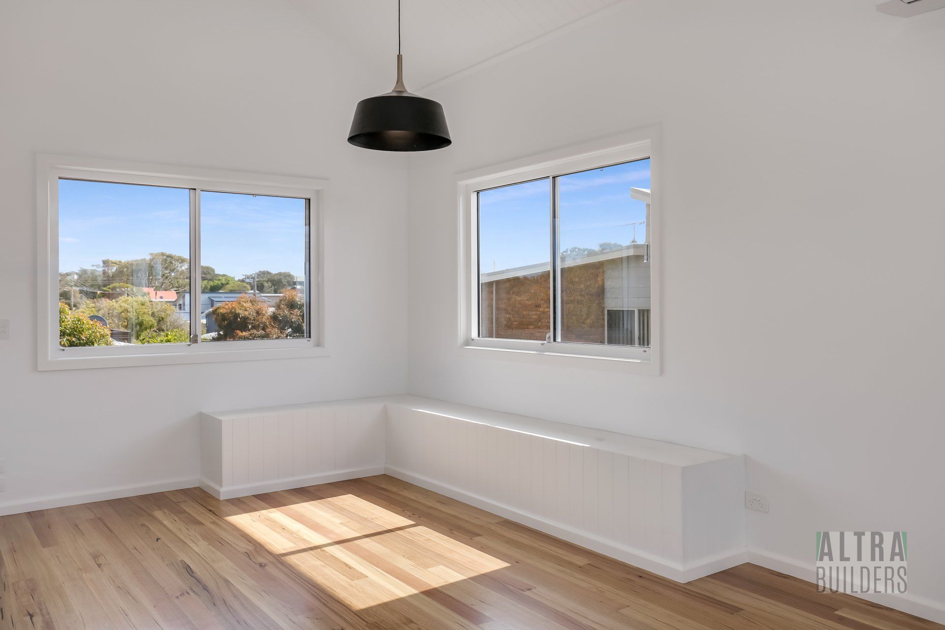 An empty room with two windows and a bench.