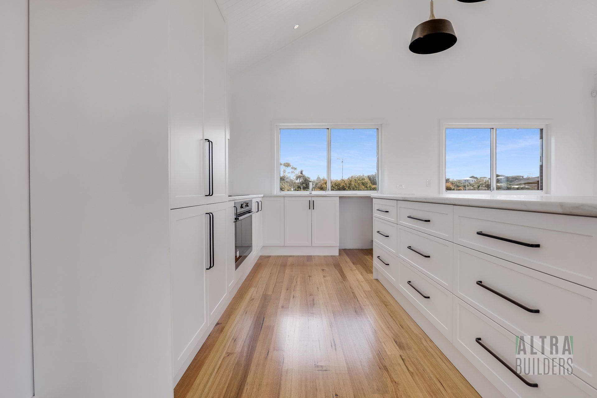 A kitchen with white cabinets and wooden floors