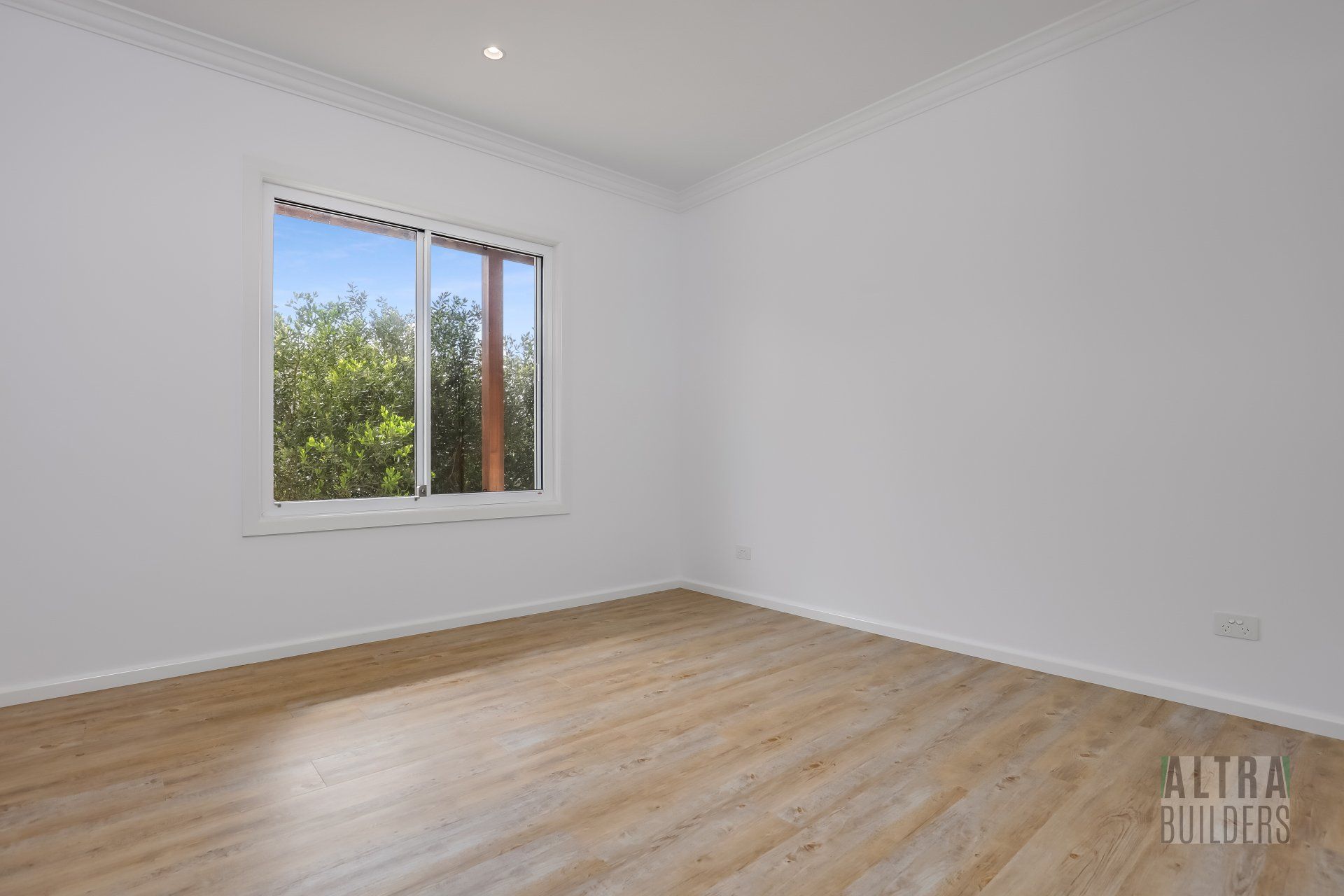 An empty room with a window and wooden floors.