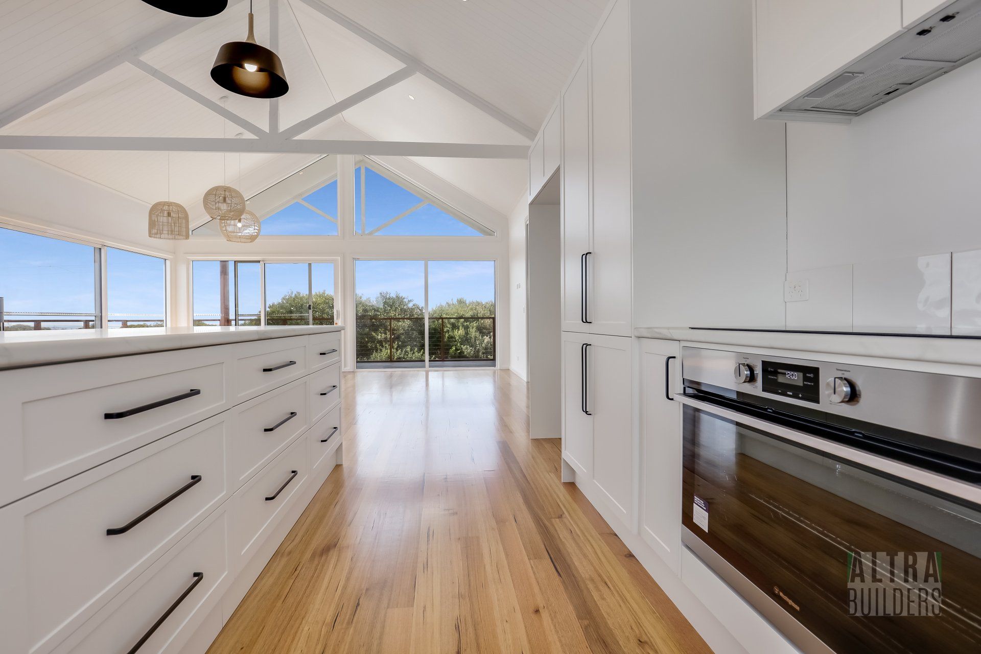 A kitchen with white cabinets , stainless steel appliances , and wooden floors.