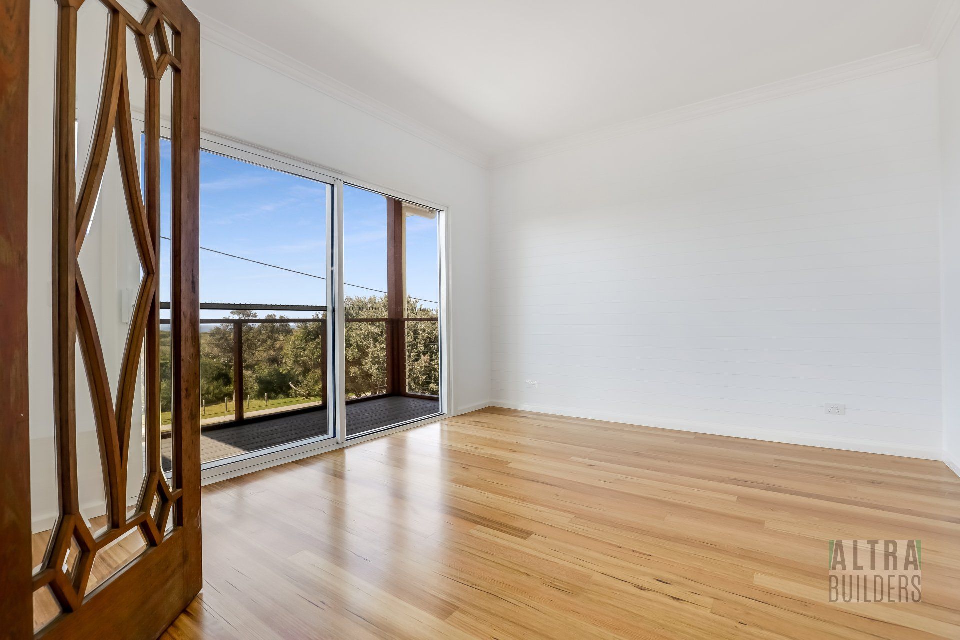 An empty living room with hardwood floors and sliding glass doors leading to a balcony.