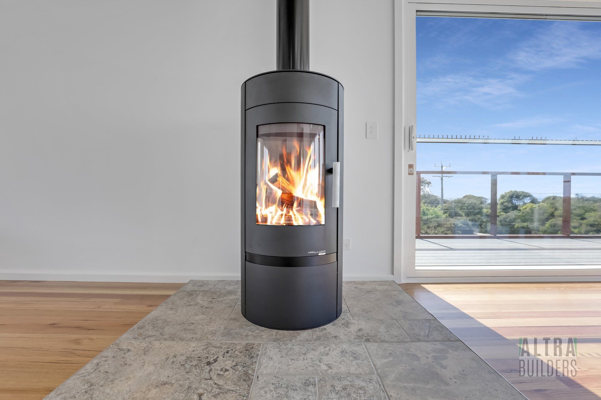 A black fireplace is sitting in an empty room next to a window.