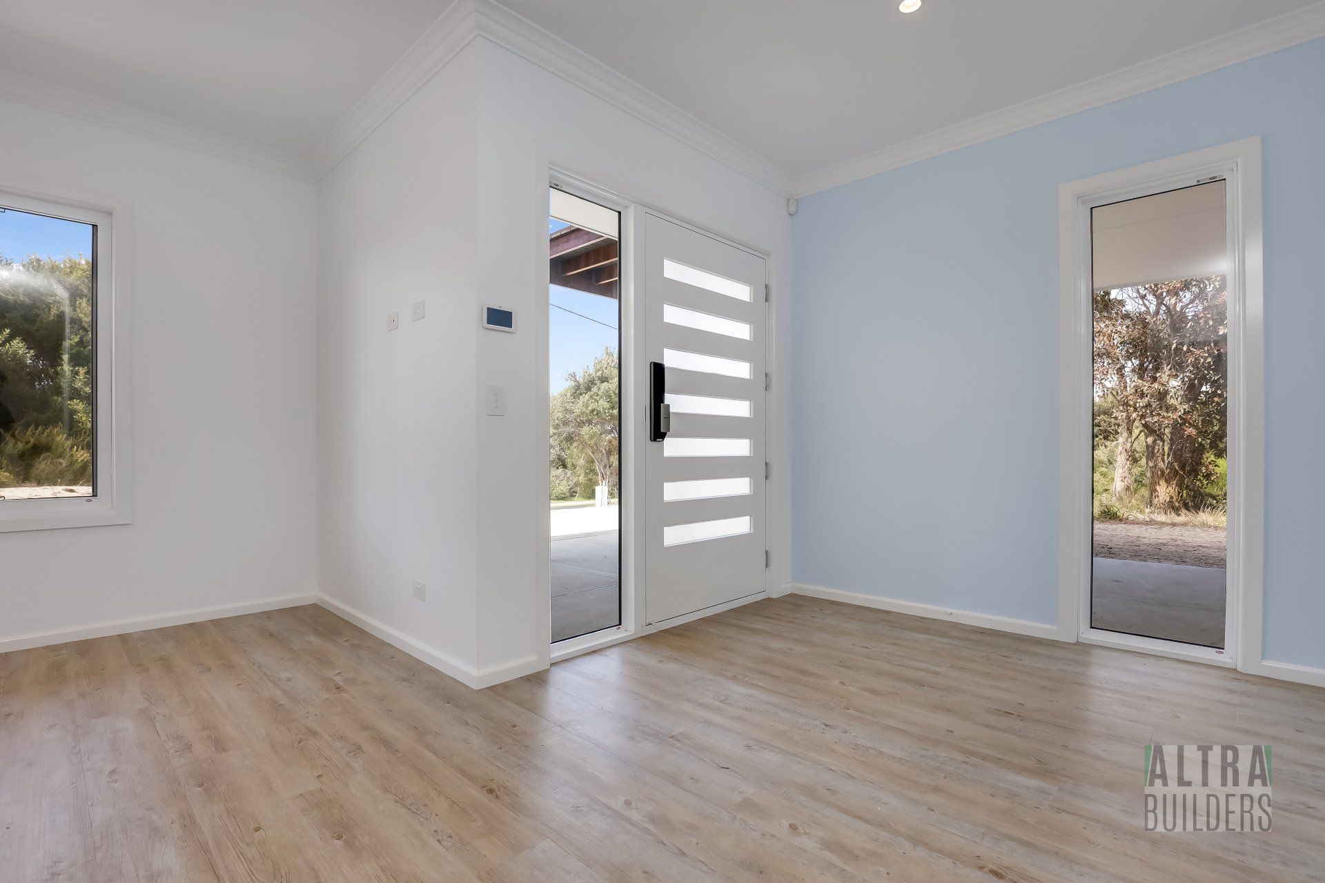 An empty room with hardwood floors and a white door.