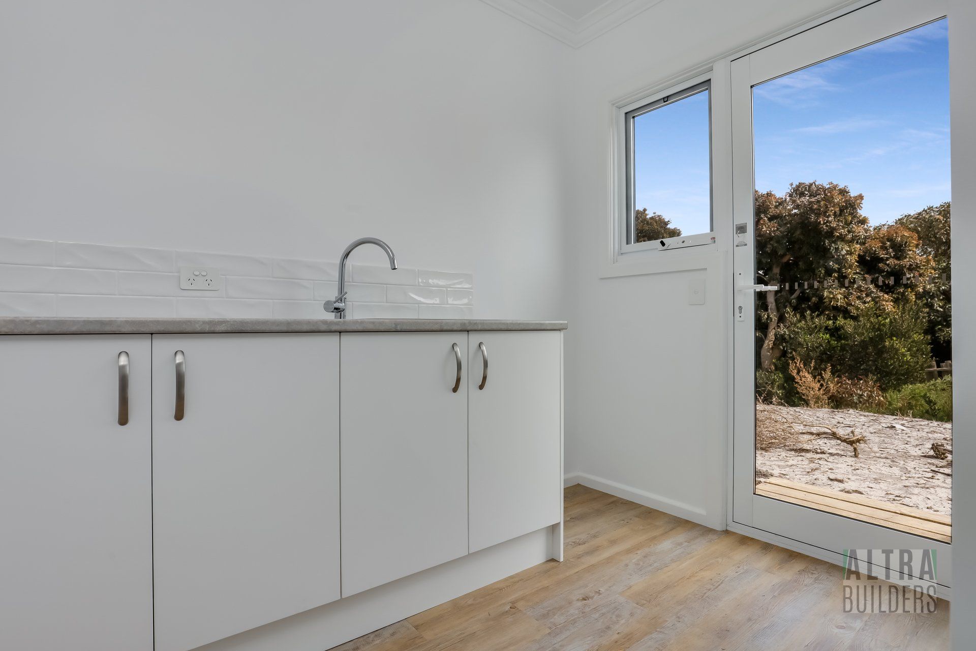 An empty kitchen with a sink , cabinets and a window.
