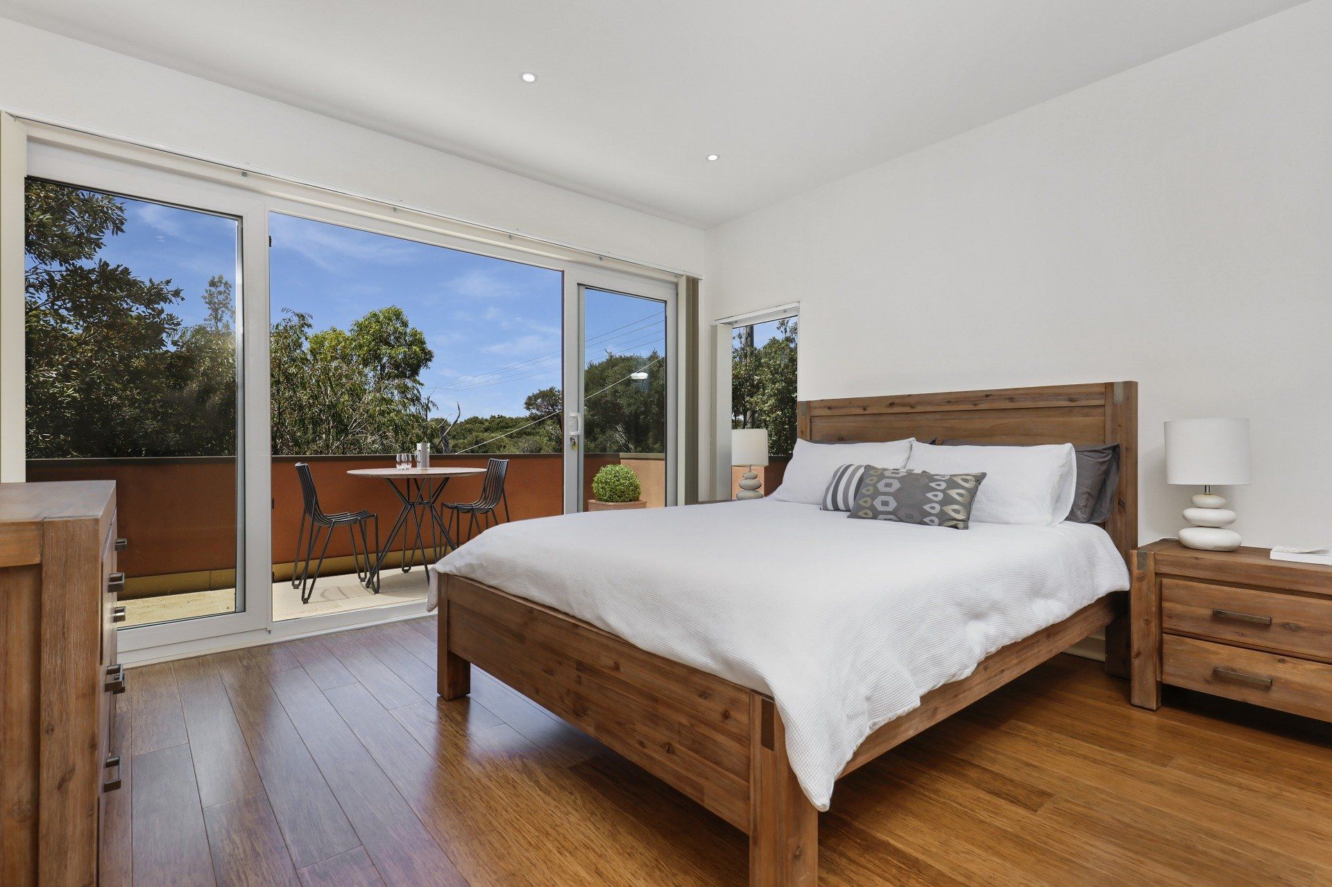 A bedroom with a bed , nightstand , dresser and sliding glass doors leading to a balcony.