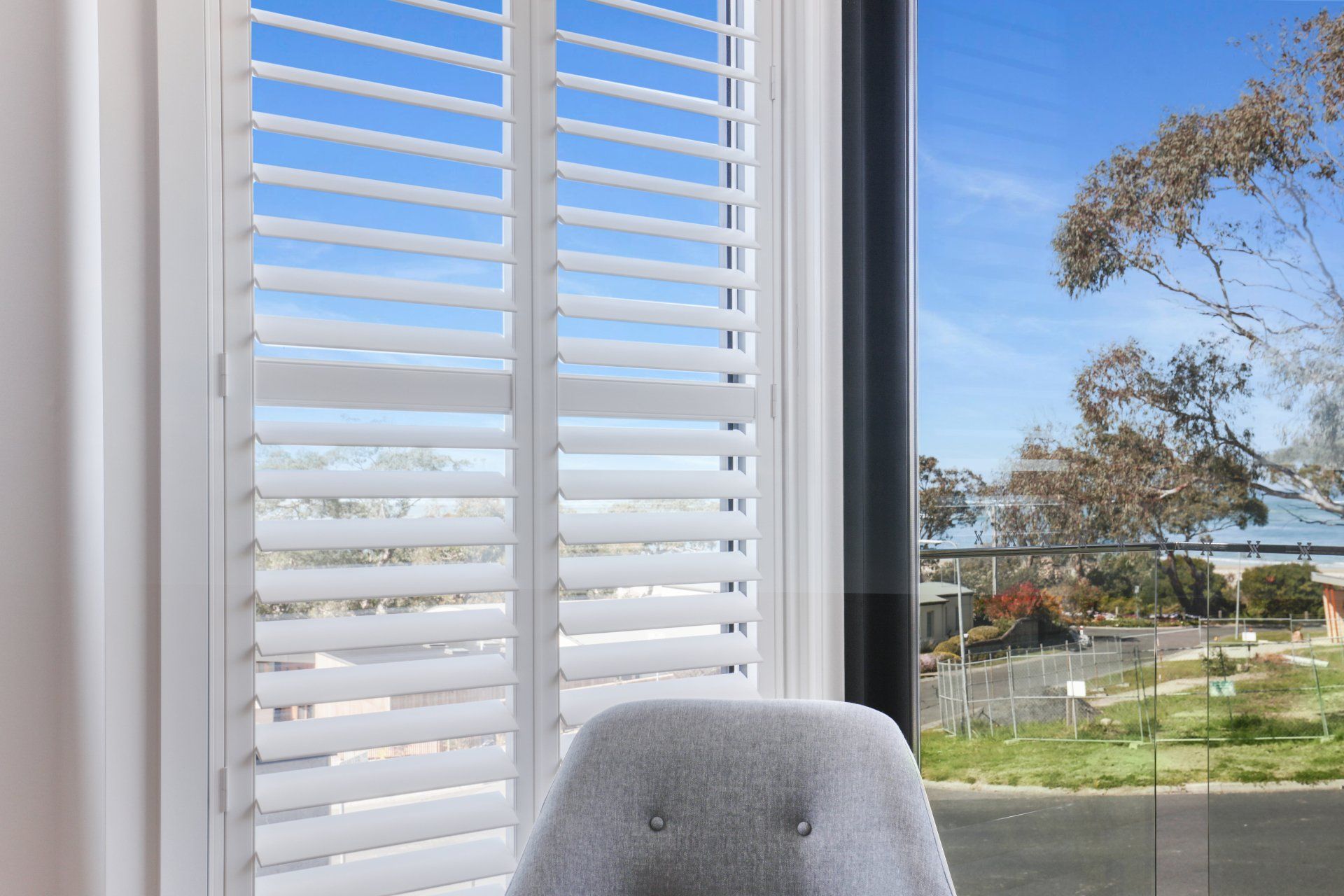A chair is sitting in front of a window with white shutters.