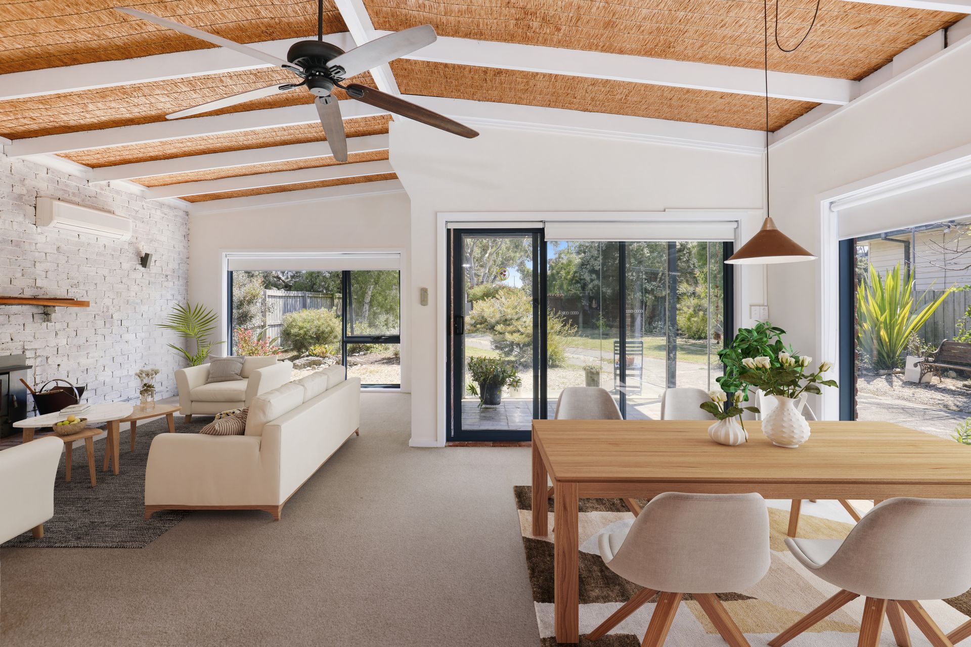 A living room and dining room in a house with a ceiling fan.