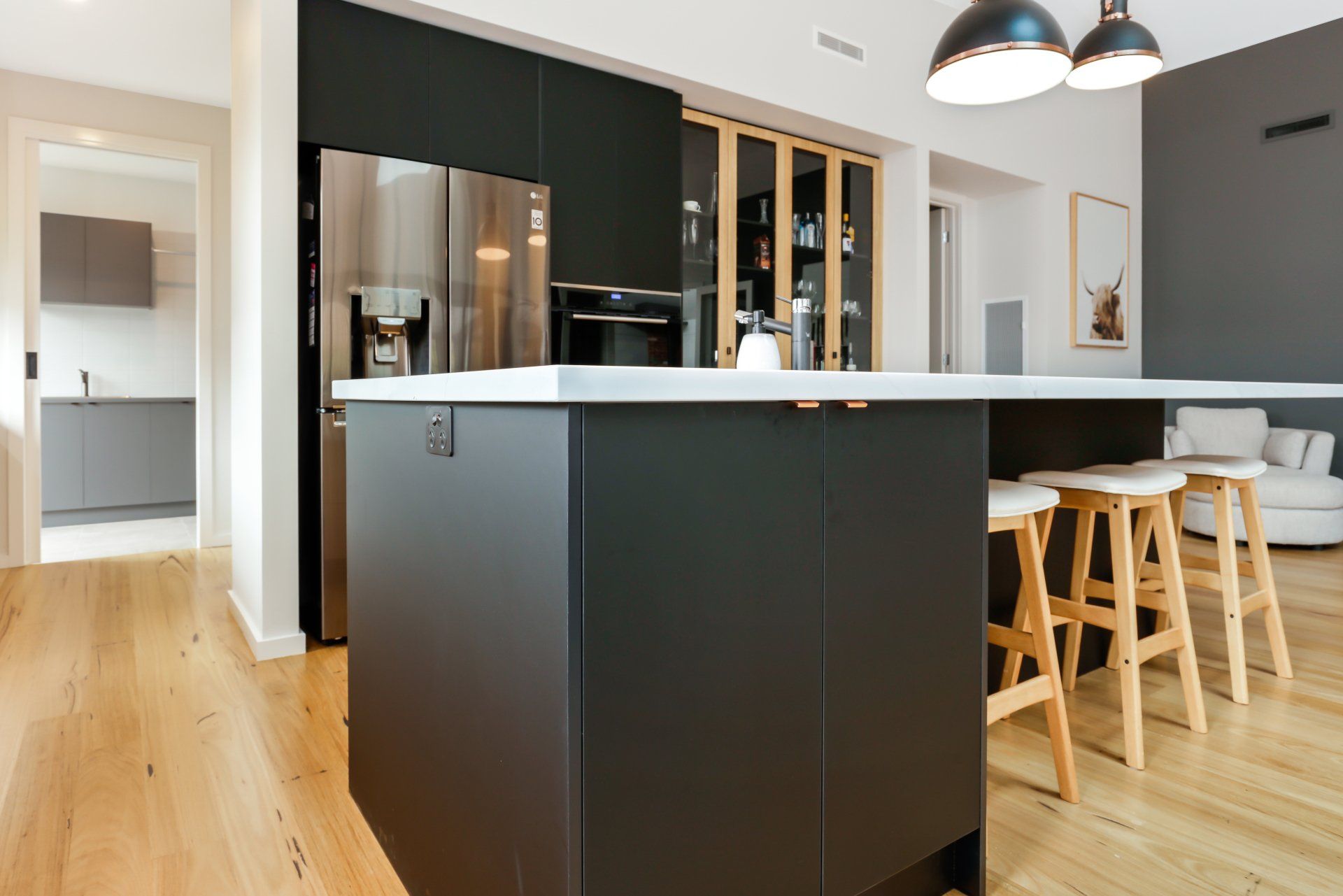 A kitchen with black cabinets and stools and a large island.