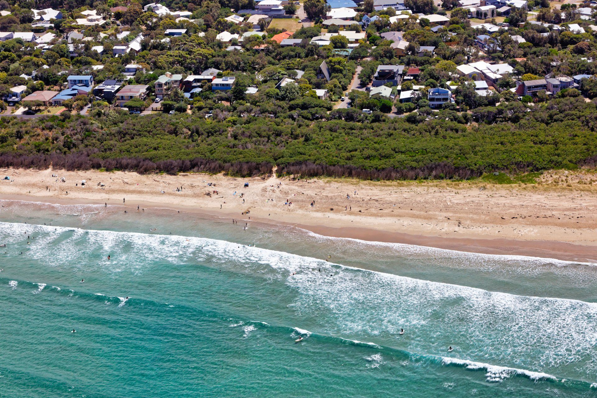 An aerial view of a beach with waves and houses in the background